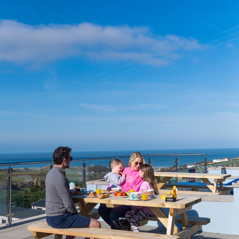 Woolacombe Sands Holiday Park Guests on Bench outside their Chalet with View of the Sea